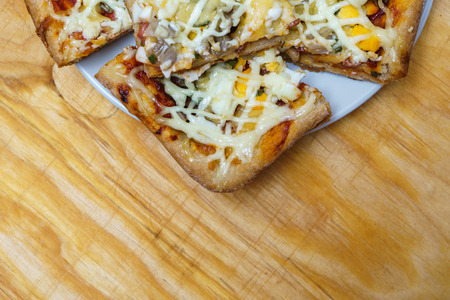 Plate with slices of homemade pizza with mushrooms and ham on wooden backgroundの写真素材