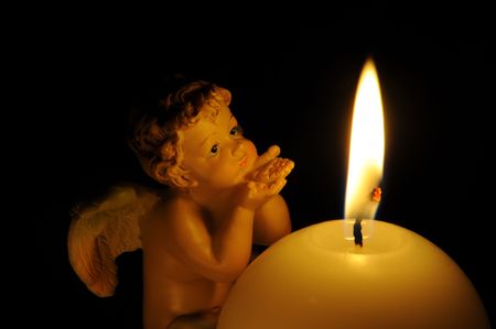 Angel at a burning candle on a black background.の写真素材