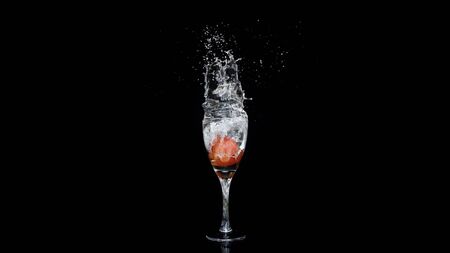 a cherry fall into wine glass and splashの写真素材