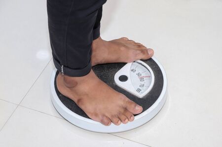 Low Section Of Man Standing On Weighing Scaleの写真素材