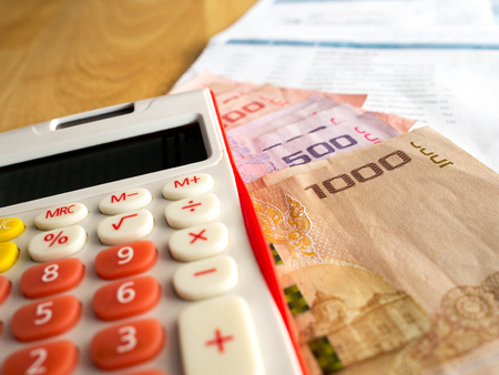 The red calculator is placed on a banknote.After calculating the bill of payment.の写真素材