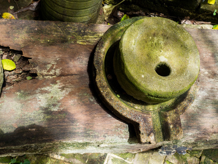 Ancient millstone have green lichen around and Ancient millstone put on old wooden boardsの写真素材