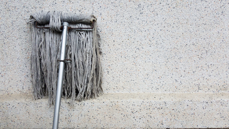 A dirty mob or swab lean on dirty concrete wall. The floor mop is used to clean the floor clean. Cleaning and exercise by housework concept.の写真素材