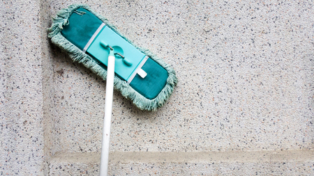 A green dirty mob or swab lean on dirty concrete wall. The floor mop is used to clean the floor clean. Cleaning and exercise by housework concept.の写真素材