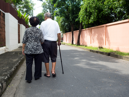 Happy romantic senior asian couple walking and holding hands on the road at the village. Concept of senior couple and take care of each otherの写真素材