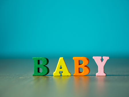 Baby. English alphabet made of wooden letter color. Alphabet baby on wooden table and background is powder blue.の写真素材