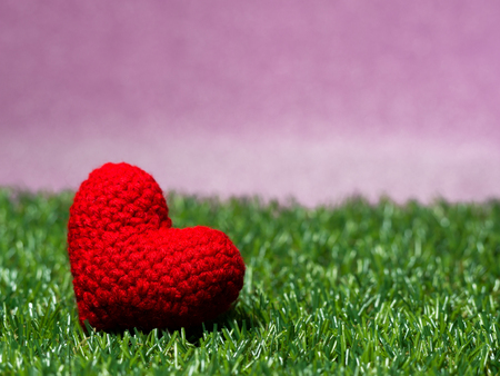 Handmade red yarn heart on Green grass background is royal pink.Copy space for text, Valentines day, love concept and love backgroundの写真素材