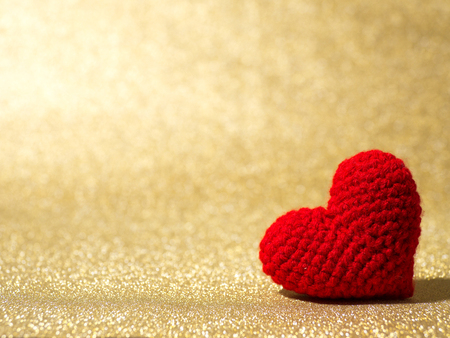Handmade red yarn heart on gold abstract background. Copy space for text, Valentines day, love concept and love backgroundの写真素材
