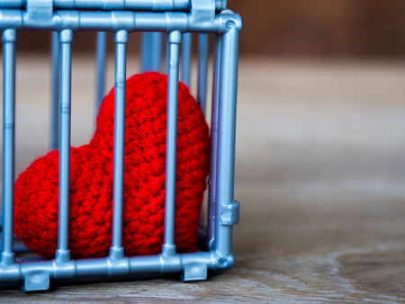 Heart in the cage Put on a wooden table, It shows the closure of freedom and love. Love is disappointed and not satisfied. Closing and blocking in loveの写真素材