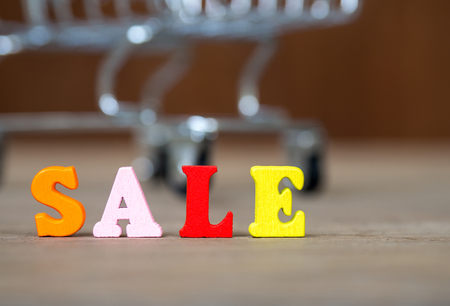 Colorful wooden word SALE on wooden table and shopping cart and background wooden. English alphabet made of wooden letter color. The concept of shopping and Discount festivalの写真素材