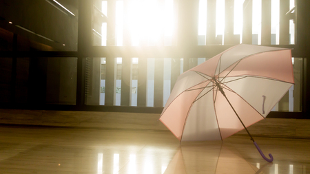 A pink and blue umbrella is placed on the floor in front of the window. Allow the umbrella to dry after rain. The window shows the sun passing through the floor.の写真素材