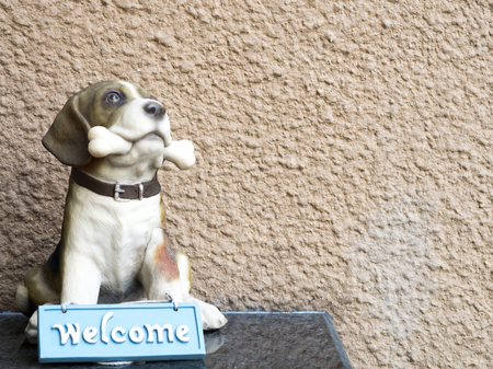 Sculpture dog bite bone and have blue welcome sign in front.の写真素材