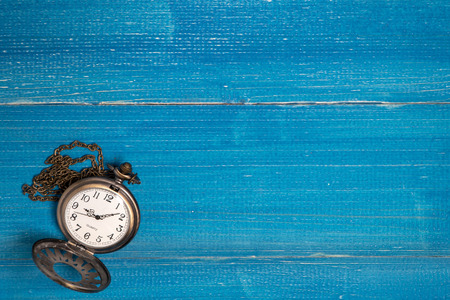 Golden vintage pocket watch put on a blue wooden tableの写真素材