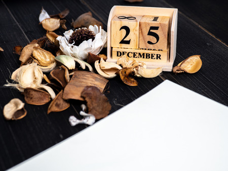 Blank notebooks are placed on a table with dried leaves and wooden block calendar set on the Christmas date 25 december on black wooden background. Concept Christmas day.の写真素材