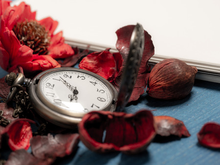 golden pocket watch put on dried leaves and blank notebook on wooden retro black table. Copy space for text and content.の写真素材