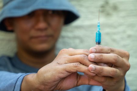 close up of Syringe and Needle in hand of drug addict man. homeless using needle injecting liquid. Drug concept and Danger of drugsの写真素材