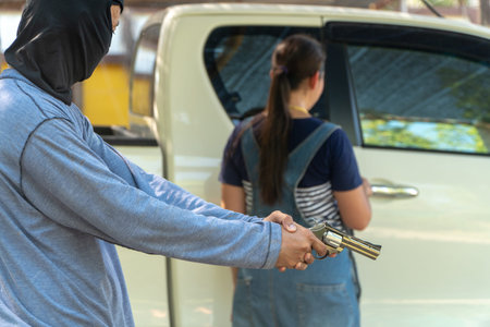 The criminals hold a gun behind the woman who is about to open the car door.Concept of social issue...