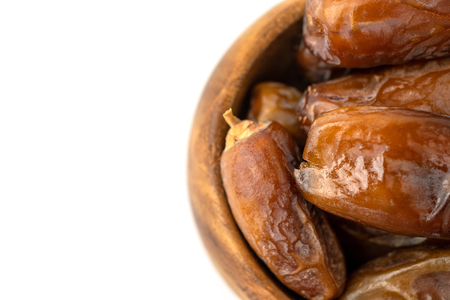 Dried of sweet dates palm fruits on wooden bowl on white background. Dates is a dried fruit that provides high energy.の写真素材