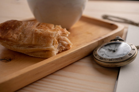 Antique gold pocket watch placed on the side of the wooden tray With a white coffee mug And the pie...