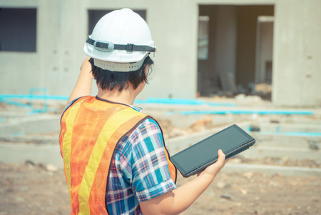 Asian women engineering holds a tablet for use in the inspection of construction sites for accuracy...