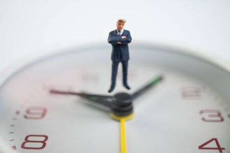 Figure businessmen are thinking And standing on the white watch face by the watch face showing the time. Concept of time management.の写真素材