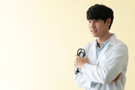 Portrait of Asian young doctor with arms crossed holding stethoscope in  hospital emergency lap. Concept of healthcare patient lifestyle and medical.の写真素材