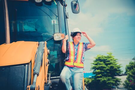 The concept of Modern women with equal ability for men. The Asian female engineer are standing on the backhoe And stood looking towards the construction site.の写真素材
