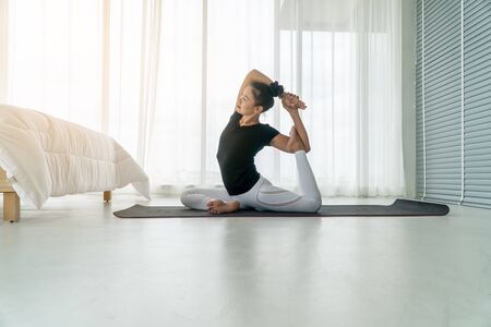 Middle aged women doing yoga in bedroom at the morning, adho mukha svanasana pose. Concept of exercise and relaxation in the morning.の写真素材