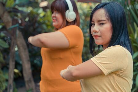 Overweight Asian women workout in the garden with her friend. Concept of Exercise to lose weight and maintain good health.の写真素材