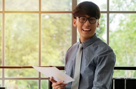 Young Asian businessman excited happy and celebrating success in the workplace after see finalizing the annual sales report. Concept of new entrepreneur successfulの写真素材