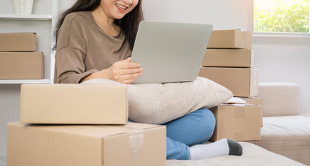Young entrepreneur, sitting on the sofa and working at home. Checking orders from customers by...