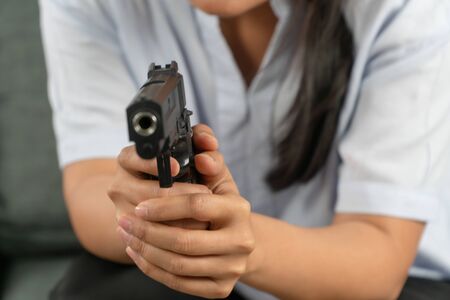Depressed middle-aged women holding a gun in living room due to stress in life and unable to find a solution and no advisor. Concepts of social issues, stress, and relationships in the family.の写真素材