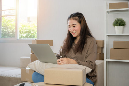 Young entrepreneur, sitting on the sofa and working at home. Checking orders from customers by...