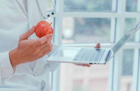 Doctors or nutritionists hold apples and laptops In the clinic To explain the benefits of fruits and vegetables. Good health starts with you. Useful food concept.の写真素材