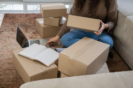 Happy young asian entrepreneurs are arranging boxes for delivering products to customers. Small...