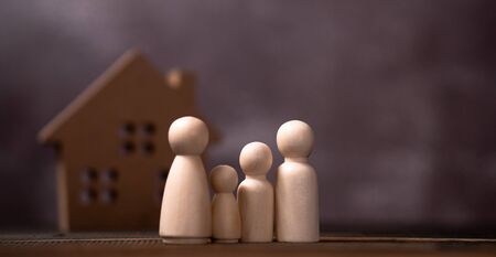 Wooden figures family standing in front of a wooden house. The concept of Protection and safety, Home Security, property insurance and house.の写真素材
