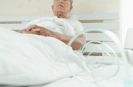 Sad senior man lying on the hospital bed and with a nasal breathing tube for treatment respiratory....