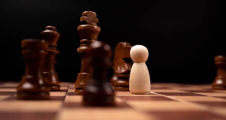 Wooden figures (businessman) standing confront of chess king and being in the chess circle. New business players are facing challenges. The management or leadership, analysis, strategy concept.の写真素材