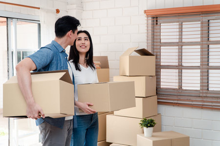 Happy smiling couple in front of the home and holding keys to New Home On Moving In Day, and start a...