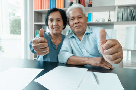 Senior Asian couple using the calculator and paperwork on desk at home to calculate expenses and income. And savings after retirement. Concept of financial planning and investment for retirees.の写真素材