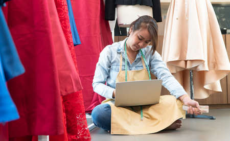 Stressed Asian entrepreneur sitting beside the window because her shop has stopped doing business. Due to financial problems And the economic slowdown. Concept of business crisisの写真素材