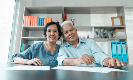 Senior Asian couple using the calculator and paperwork on desk at home to calculate expenses and income. And savings after retirement. Concept of financial planning and investment for retirees.の写真素材