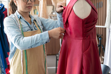 Asian woman dressmaker fashion designer measuring size of mannequin in showroom. Concept of...