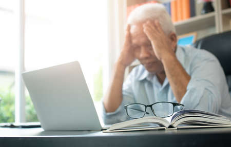 Happy senior Asian using the laptop for calculating and make a note of daily expenses. Concept of lifestyle, learning, and finance businessの写真素材