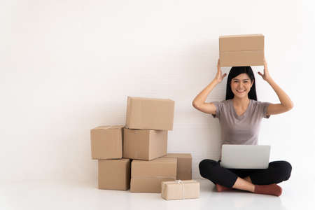 Happy Asian young entrepreneur, Smile for sales success after checking order from online shopping store at home office, Concept of merchant  business online, eCommerce and delivery and lifestyleの写真素材