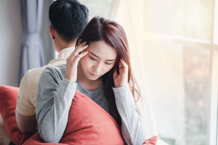 Unhappy Couple sitting behind each other on the couch and avoid talking or looking at each other, Cause of relationship problems and having misunderstanding or disagreement. Family problems conceptの写真素材