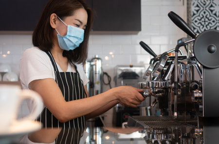 Asian barista woman wearing face masks  and brewing coffee.の写真素材