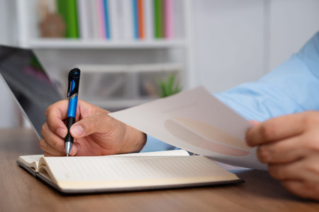 Asian Businessman Writing a business plan After looking at the annual profit and loss summary...