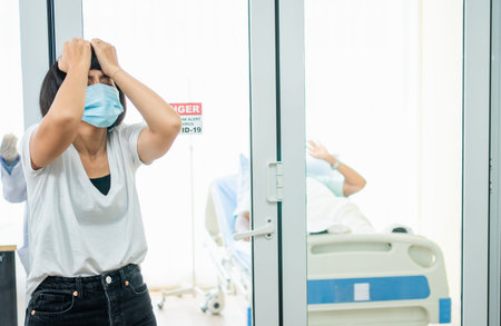 A Wife standing in front of the Quarantine room And Hold your head with her hands While waiting for...