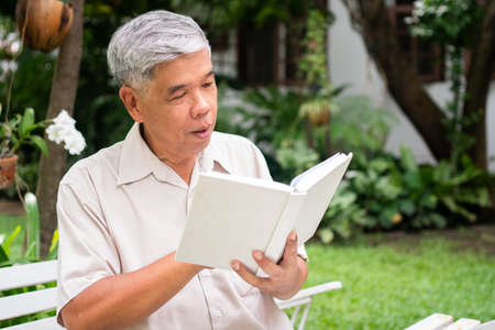 senior old man reading a book in the park. Concept of retirement lifestyle and hobby.の写真素材